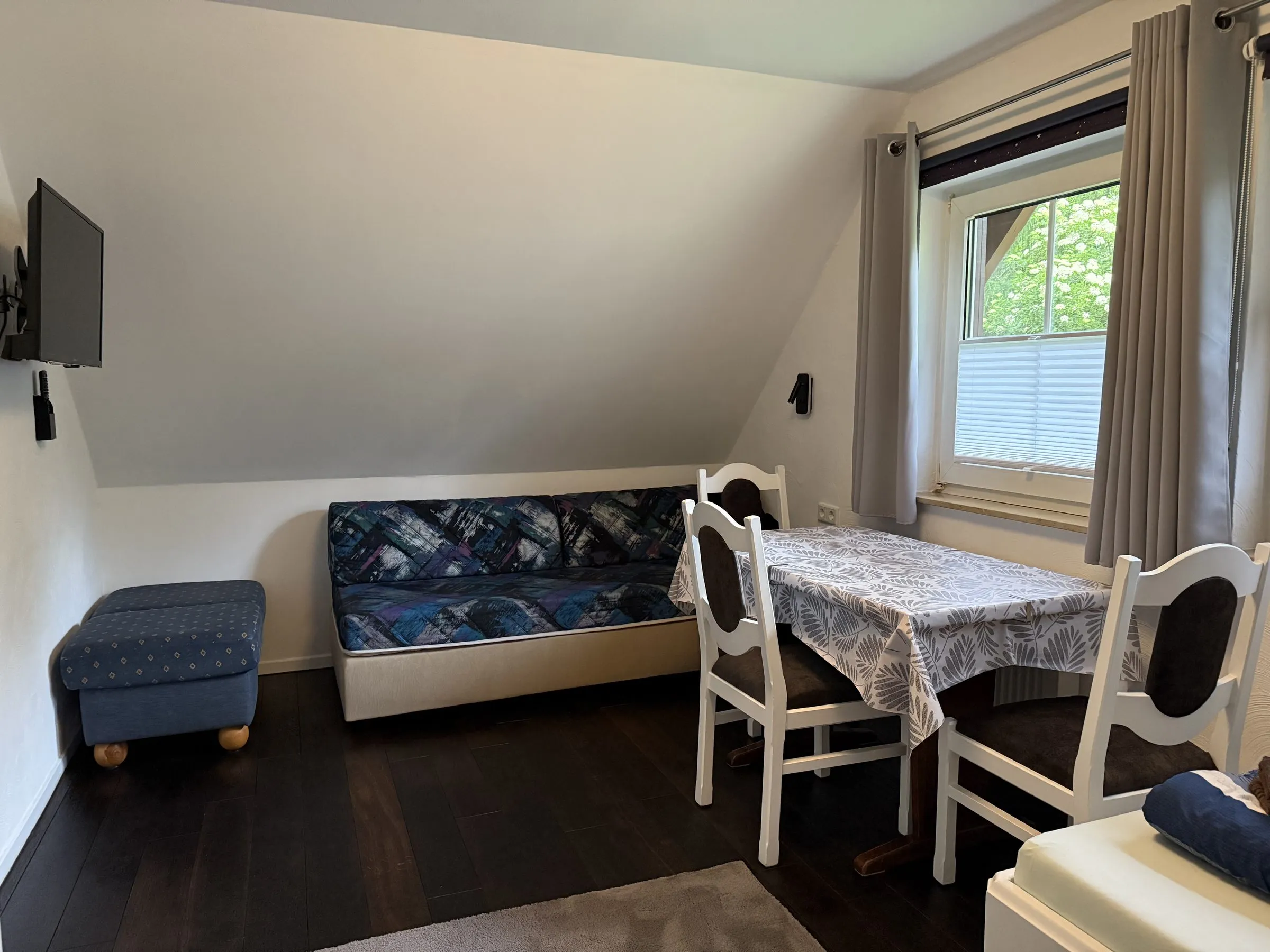 Schlafzimmer 2 im Dachgeschoss mit Sitzecke, Tisch und Smart-TV