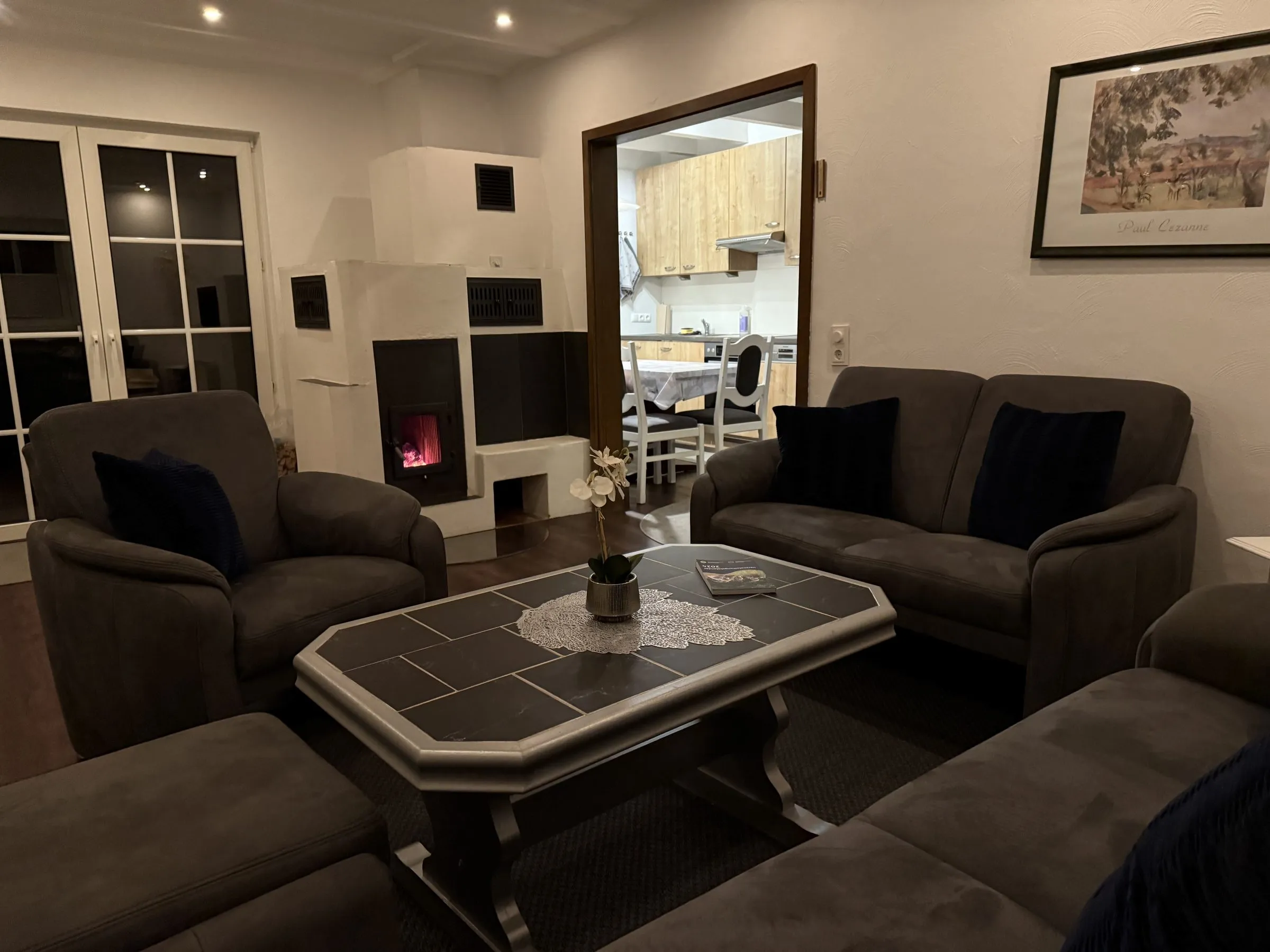Wohnzimmer mit Sofalandschaft und brennendem Holzofen